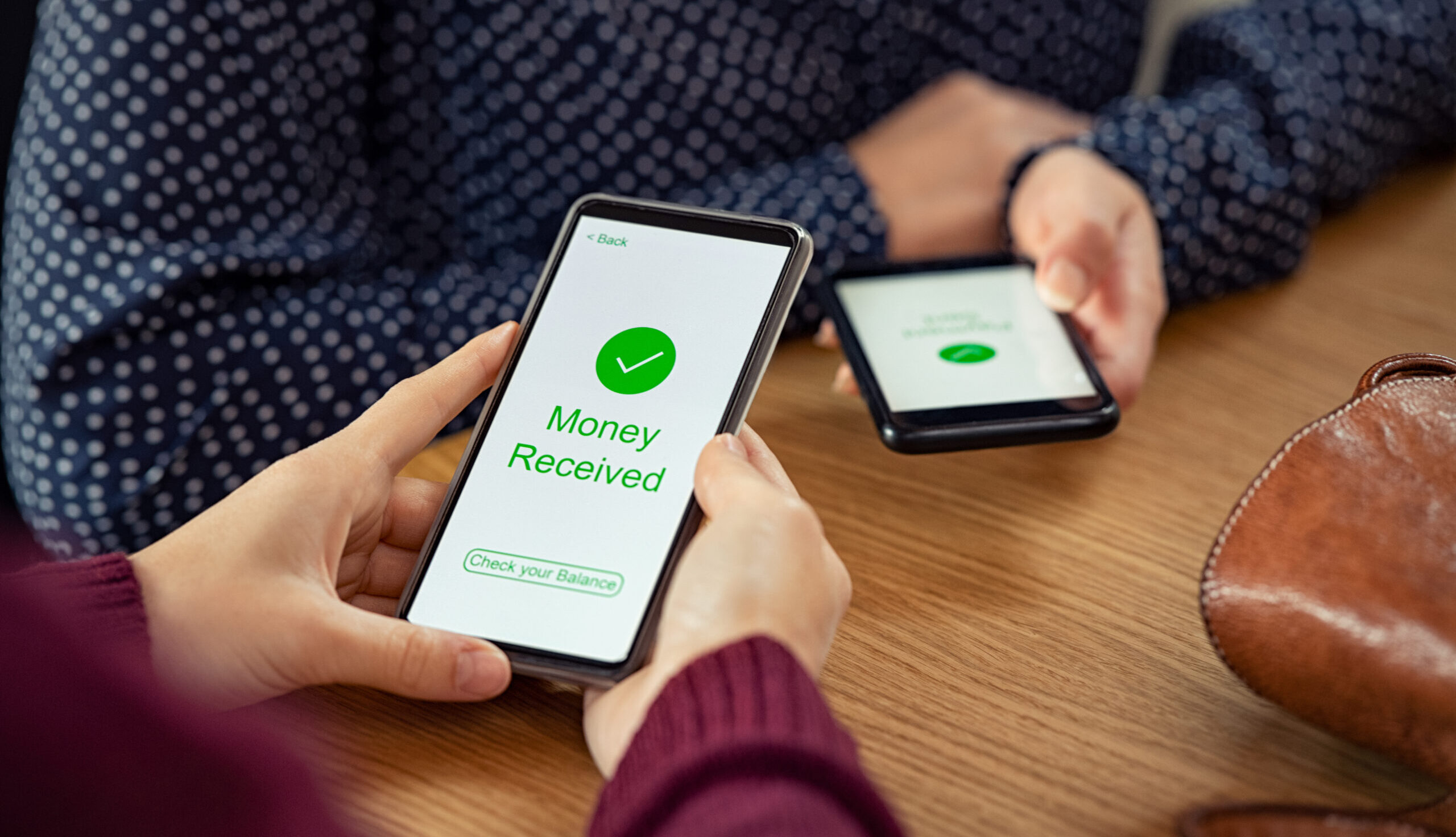 Close up of hands holding mobile phone with an application open stating that money was received.